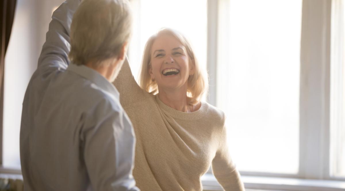 Felice donna matura di mezza età che si diverte a ballare con il marito anziano a casa