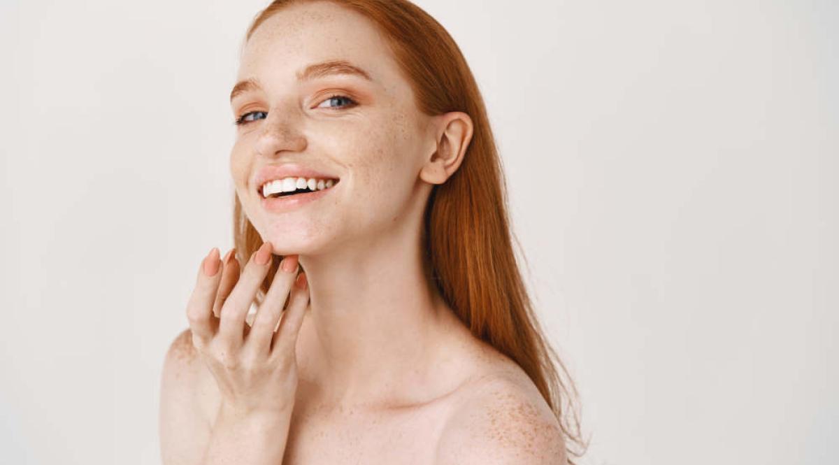 Primo piano di donna rossa sorridente con pelle pallida e lentiggini